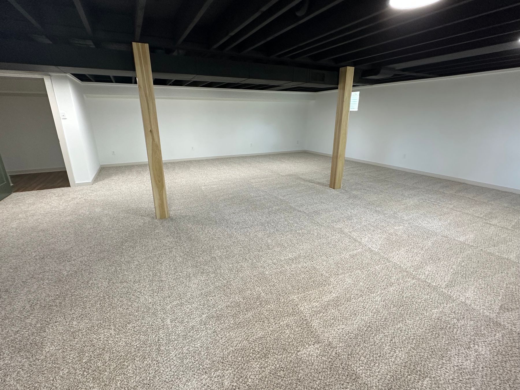 Finished basement with painted black ceiling and warm lighting — basement finishing by Pinpoint Home Services