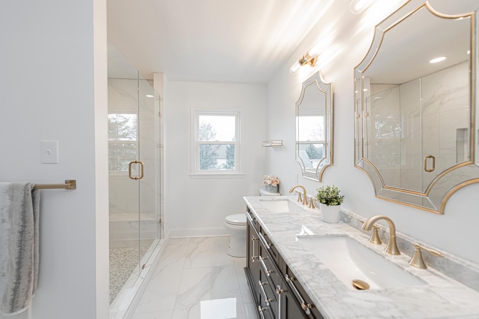 Double vanity bathroom with brass fixtures and marble surfaces — Pinpoint Home Services